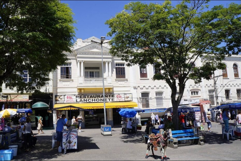 Praça com restaurante, lanchonete e barracas de ambulantes sob árvores em Aparecida, interior de São Paulo