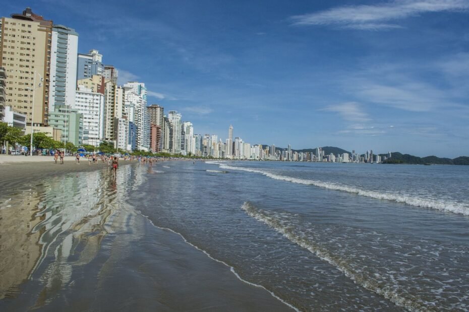Areia molhada da Praia Central e a extensa fileira de prédios da orla de Balneário Camboriú (SC)