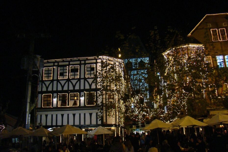Prédios em estilo enxaimel com luzes decorativas e mesas de bares à noite na Vila Capivari, Campos do Jordão