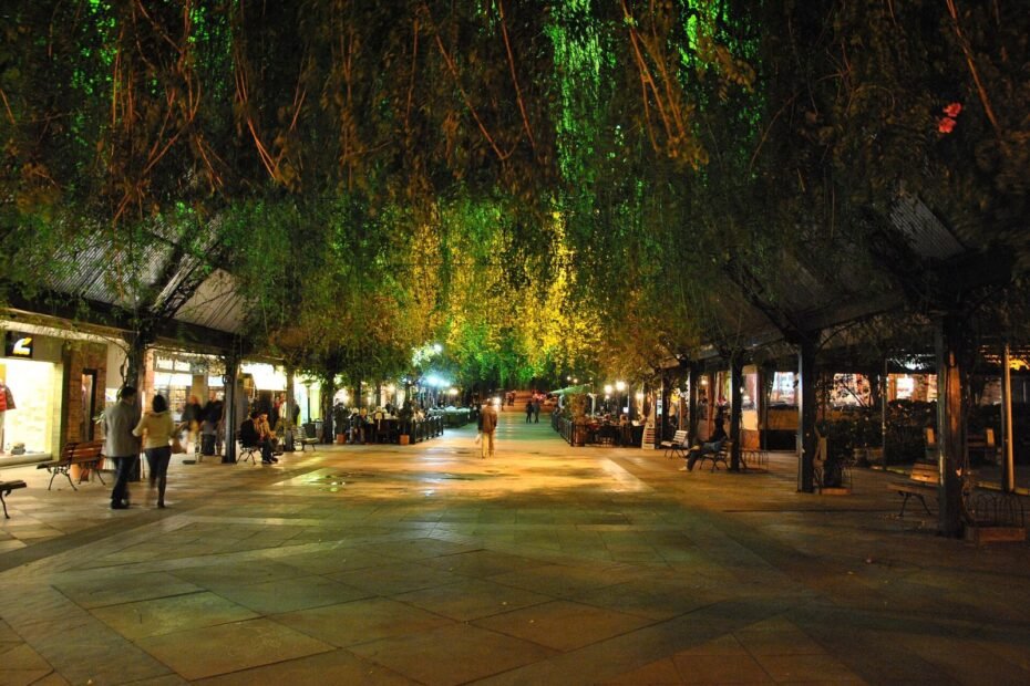 Rua Coberta de Gramado à noite, com teto tomado por trepadeiras e lojas e cafés iluminados (RS)