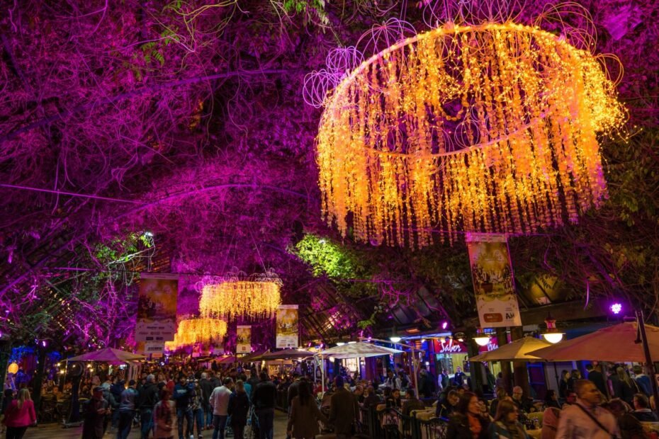 Rua Coberta de Gramado iluminada com lustres de luzes douradas e árvores em tons de roxo durante o Natal Luz