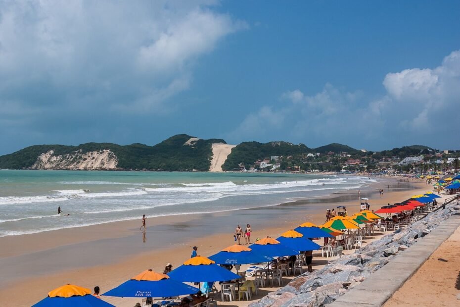 Praia de Ponta Negra com guarda-sóis na areia e o Morro do Careca ao fundo, em Natal (RN)
