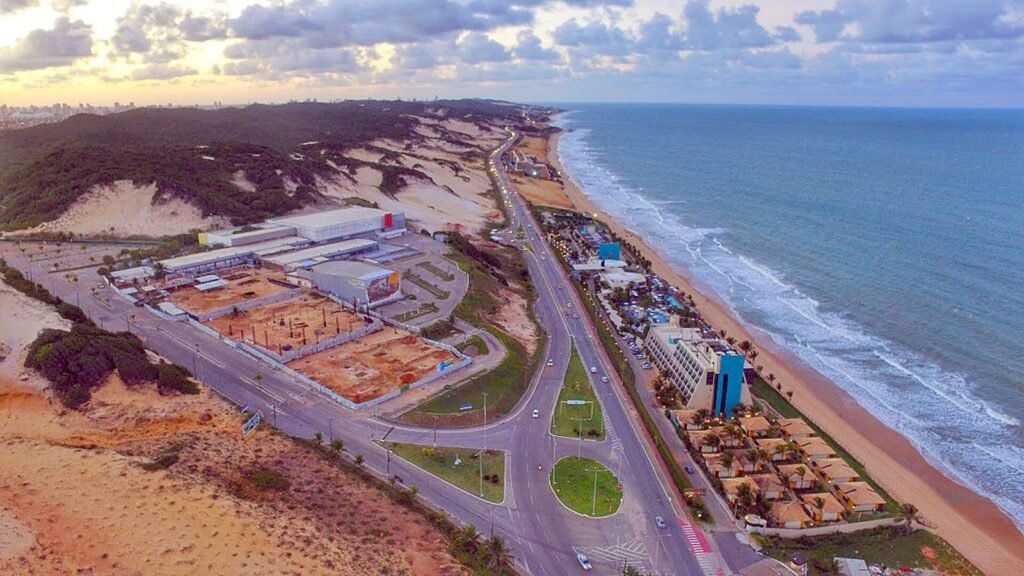 Vista aérea da Via Costeira, entre as dunas e o mar, com hotéis à beira-mar em Natal (RN)