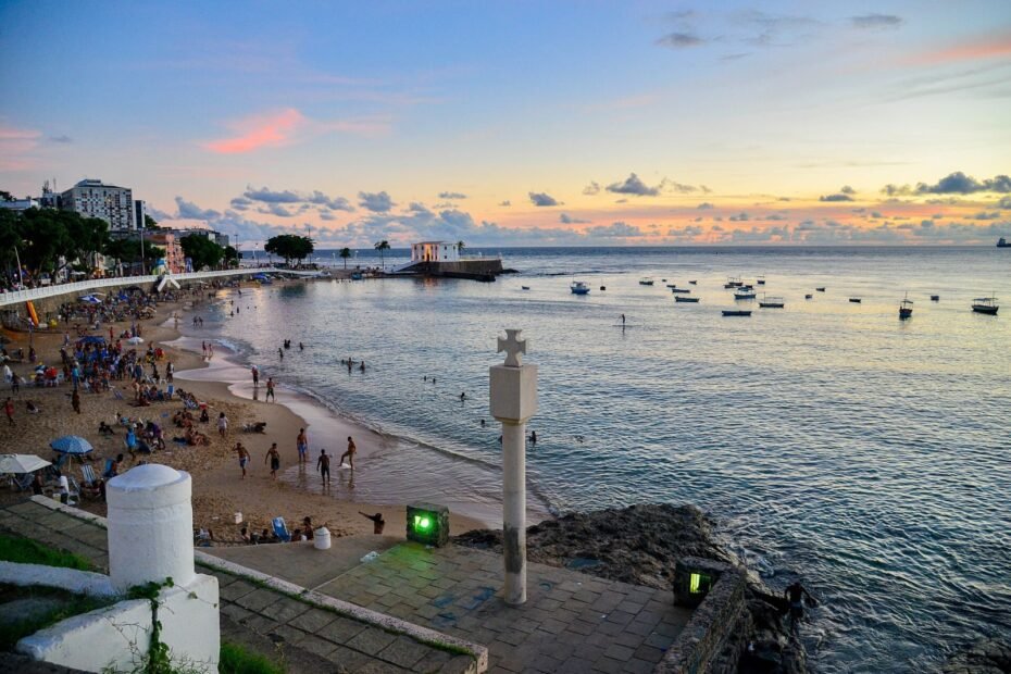 Porto da Barra ao entardecer, com barcos, mar calmo e o Forte de Santa Maria, em Salvador