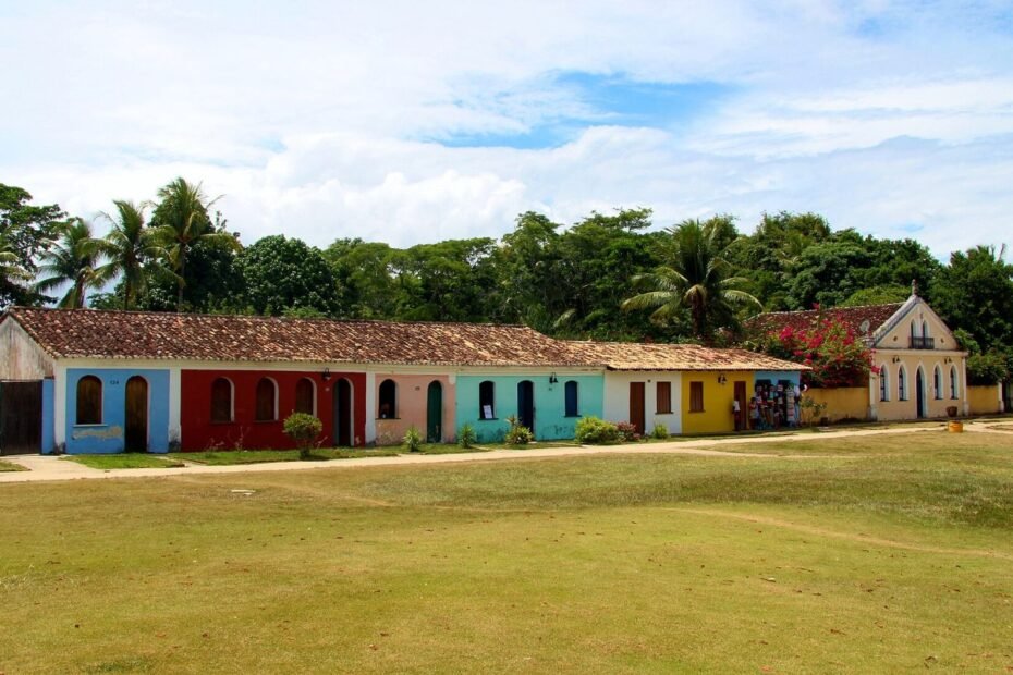Casario colonial colorido em torno de um gramado na Cidade Histórica de Porto Seguro (BA), sob céu azul