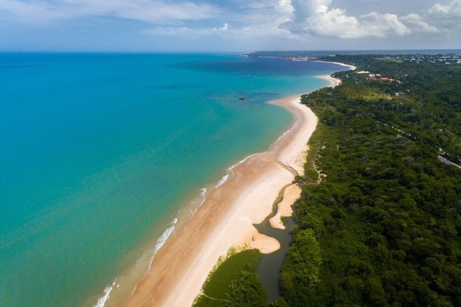 Vista aérea da Praia de Mundaí com mar azul-turquesa, faixa de areia e mata nativa em Porto Seguro (BA)