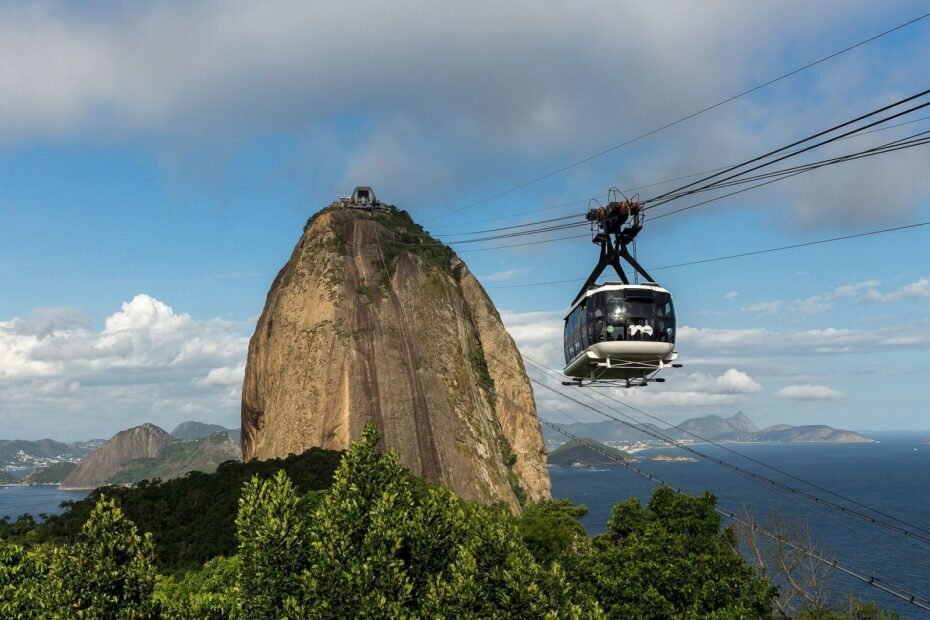 Bondinho suspenso diante do Pão de Açúcar, com o mar e montanhas ao fundo, no Rio de Janeiro