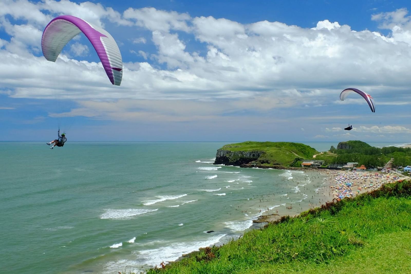 Parapentes sobrevoam o mar diante do Parque da Guarita e da Praia da Cal, em Torres (RS)